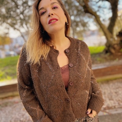 Casaco castanho felpudo com losangos brancos sobre camisola castanha e calças estampadas animal