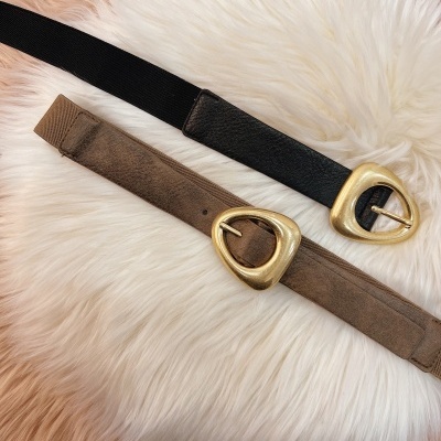 Duas cintas femininas com fivelas douradas triangulares sobre superfície felpuda branca e bege.