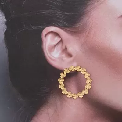Brinco argola dourado com flores na orelha de mulher