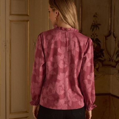 Blusa rosa com padrão floral em relevo e mangas compridas com punhos franzidos vista de costas