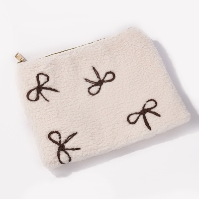 Estojo branco felpudo com laços pretos bordados e fecho dourado