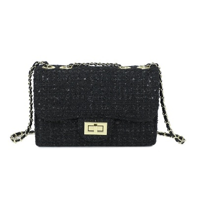 Mala preta de tecido com fecho dourado e alça em corrente.