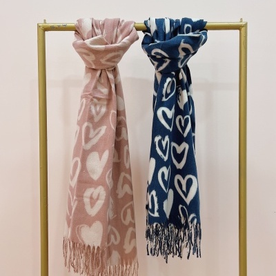 Dois cachecóis cor-de-rosa e azul com padrão de corações pendurados em cabide amarelo