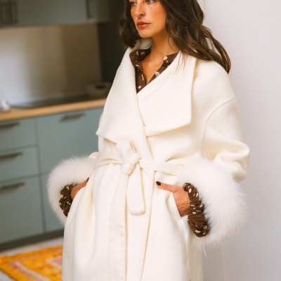 Casaco branco com cinto e punhos de pelo sobre vestido castanho às bolinhas