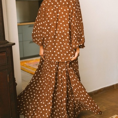 Vestido castanho com bolinhas brancas e saia plissada visto de costas