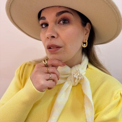 Mulher com chapéu bege, camisola amarela e lenço decorativo