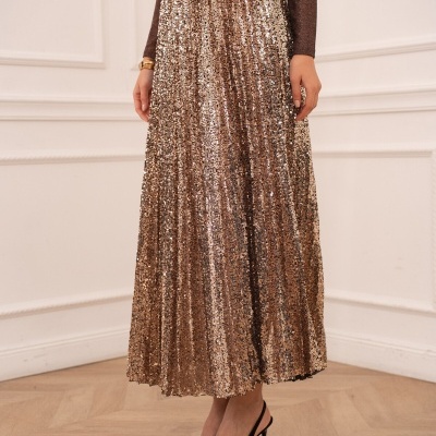 Saia longa plissada dourada com lantejoulas, camisa castanha metálica, sapatos pretos salto alto