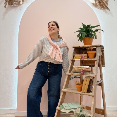 Pessoa com roupa casual perto de escada com plantas e livros