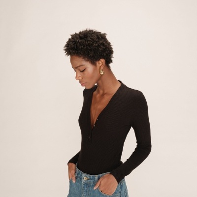 Mulher com camisola preta de manga comprida e saia de ganga azul