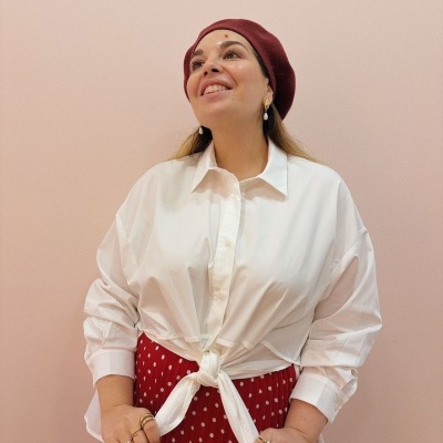 Mulher com boina vermelha, camisa branca com nó e saia vermelha de bolinhas brancas