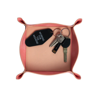 Bandeja de couro rosa com molho de chaves e chaveiro preto com texto