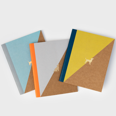 Três cadernos com capas marrons e detalhes coloridos, cada um com uma silhueta de cão dourada