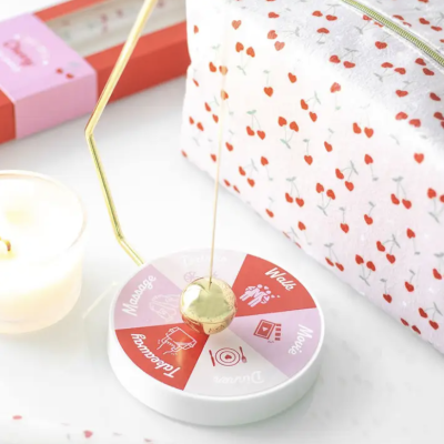 Pêndulo dourado sobre disco branco com palavras e bolsa branca com padrão de cerejas