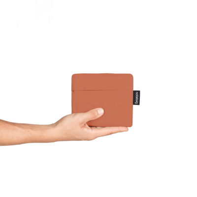 Carteira castanha com etiqueta preta a ser segurada por uma mão sobre fundo branco