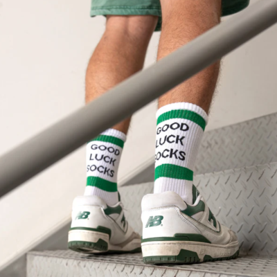 Meias brancas e verdes com texto 'GOOD LUCK SOCKS' usadas com sapatilhas New Balance