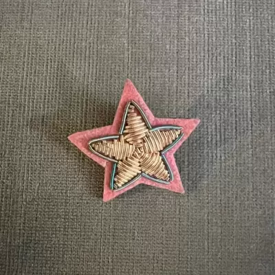 Estrela decorativa em tecido e material trançado sobre fundo cinzento