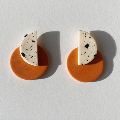 Par de brincos geométricos laranja e branco com manchas pretas