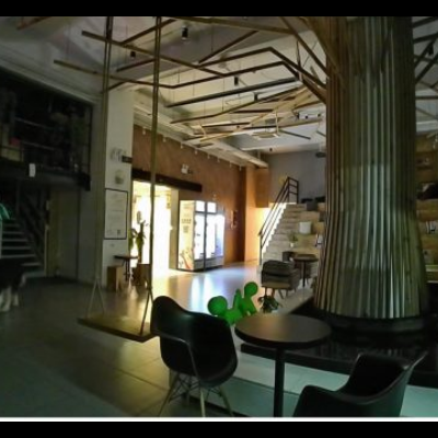 Interior de espaço com mesa, cadeiras, coluna central e um cão no chão