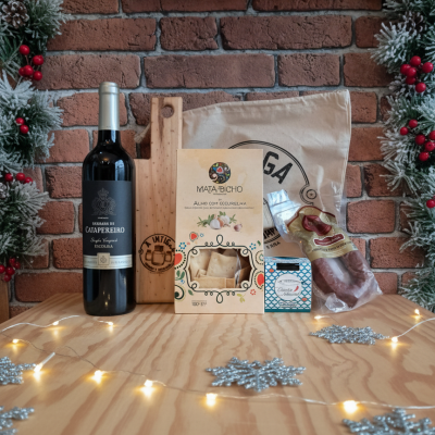 Produtos gourmet dispostos numa mesa de madeira com decoração natalícia de pinheiro, bagas vermelhas e luzes brancas.