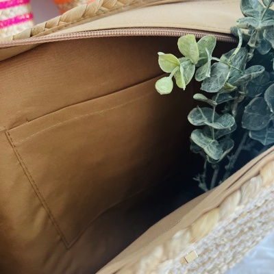 Interior de mala trançada bege com planta artificial e bolso castanho