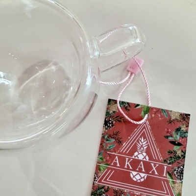 Xícara de vidro transparente com etiqueta vermelha AKAXI