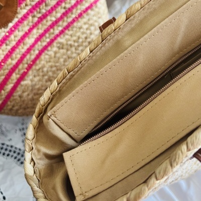 Bolsa de palha com interior bege e fecho de correr e bolsa trançada bege com riscas cor-de-rosa fundo desfocado
