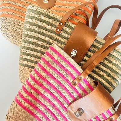 Três malas de palha trançada com tiras coloridas e alças em castanho