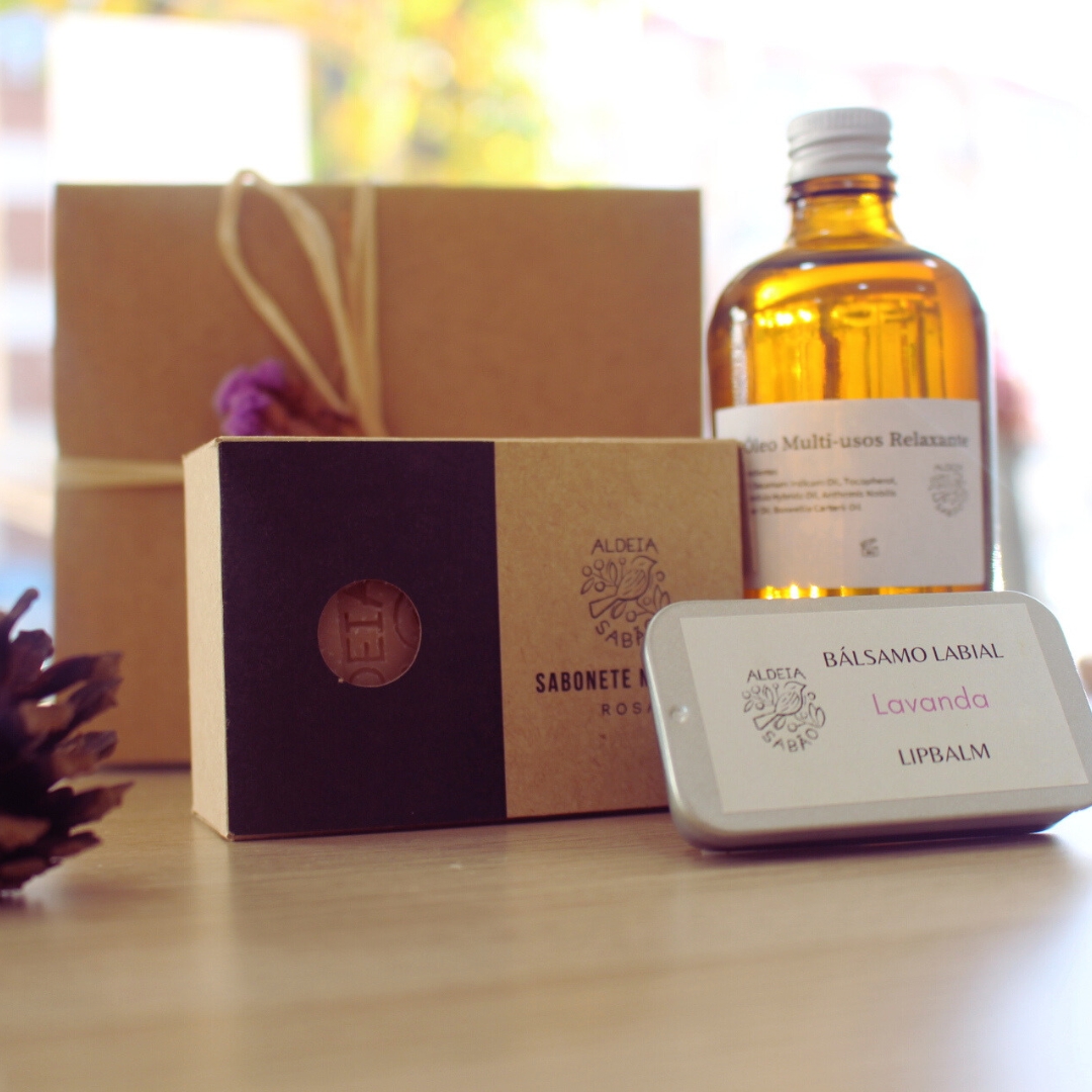 Kit Cuidado e Amor Produtos de beleza naturais em embalagem de cartão e lata com frasco âmbar em fundo desfocado