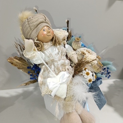 Boneco decorativo com roupa bege e branca e ramo de flores secas azuis e brancas