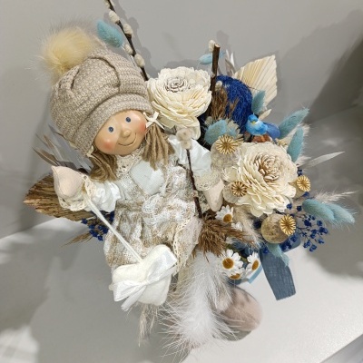 Boneco decorativo com gorro bege e flores artificiais em arranjo colorido