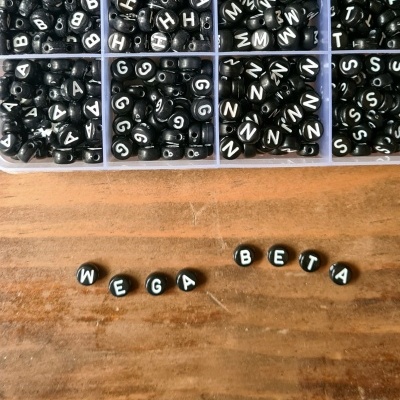 Contas pretas de enfiar com letras do alfabeto