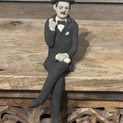 Figura decorativa de homem de fato preto sentado em madeira entalhada