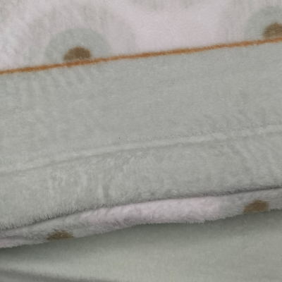 Manta felpuda em tons bege e rosa com padrão de bolas.