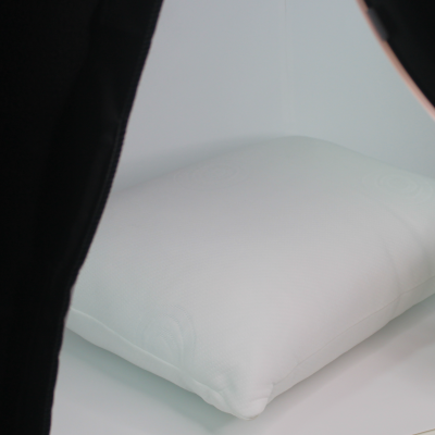 Almofada branca quadrada em superfície branca com iluminação de estúdio e planta decorativa