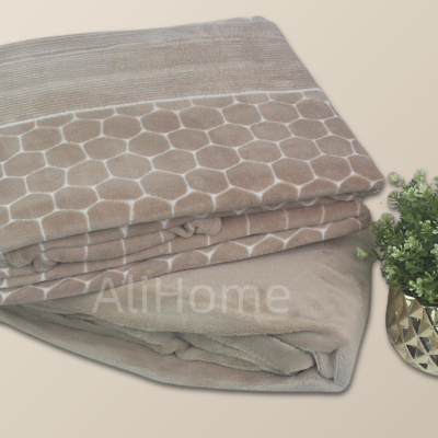 Manta bege com padrão hexagonal e vaso dourado com plantas verdes