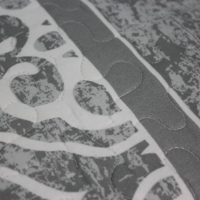 Cobertor cinza e branco com padrão abstrato e acolchoado