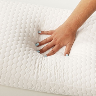 Almofada branca com padrão geométrico e mão a pressioná-la