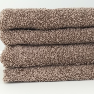 Toalhas castanhas empilhadas em superfície branca