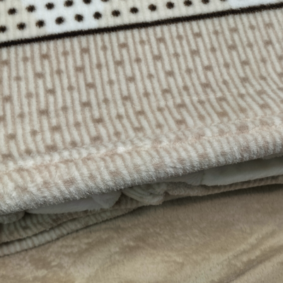 Tapete ou manta com padrões e texturas em bege e branco.