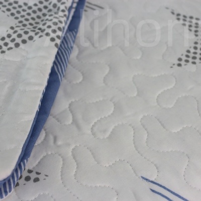 Colcha ou edredão branco com estrelas cinzentas e riscas azuis, textura costurada.