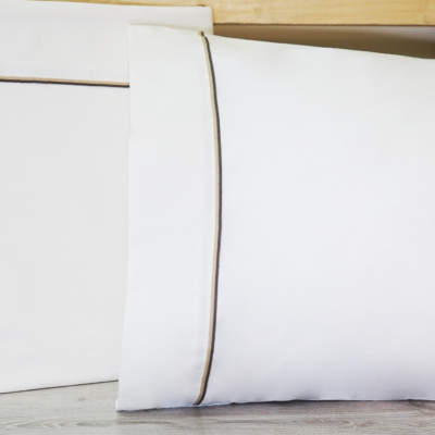 Conjunto de almofadas brancas com borda fina cinza sobre piso cinzento claro