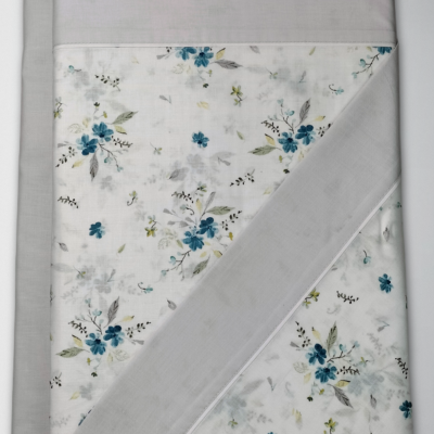 Cobertor dobrado com padrão floral azul e cinza e borda cinza