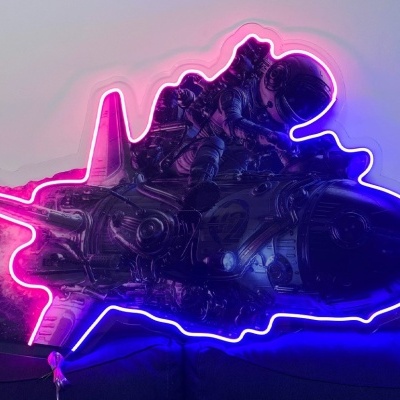 Iluminação de néon em forma de avião com luzes rosa, púrpura e azul sobre sofá preto