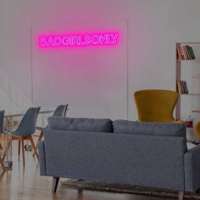 Sala moderna com sofá cinza, poltronas amarelas e letreiro em néon rosa BADGERJ ONLY