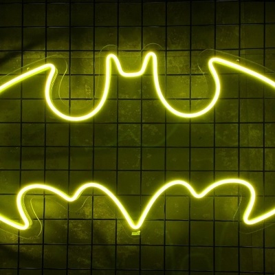 Letreiro néon amarelo símbolo do Batman numa parede de azulejos
