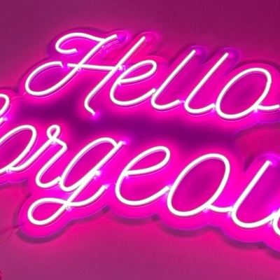 Letreiro néon rosa com texto 'Hello Gorgeous' montado na parede