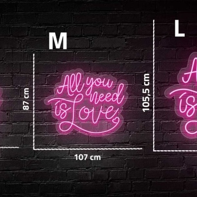 Três letreiros de néon cor-de-rosa com texto 'All you need is Love' em tamanhos S, M e L numa parede de tijolos pretos
