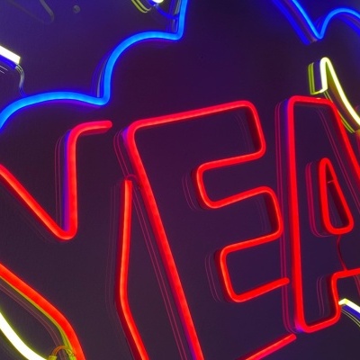 Sinal de néon com a palavra YEAH em vermelho com contorno azul, amarelo e branco