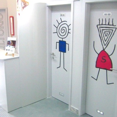 Portas com desenhos estilizados de figuras humanas em escritório com sinalização 'AUDITÓRIO'