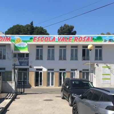 Edifício branco com placas coloridas e carros estacionados em frente